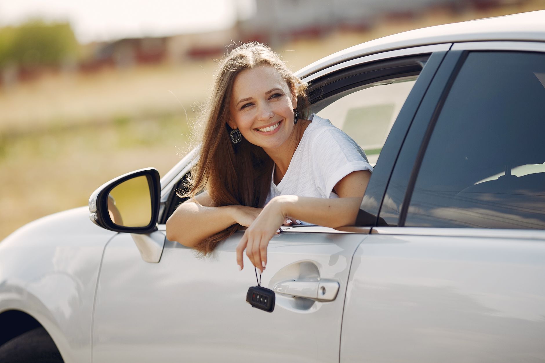 happy woman with car key in modern automobile during car trip